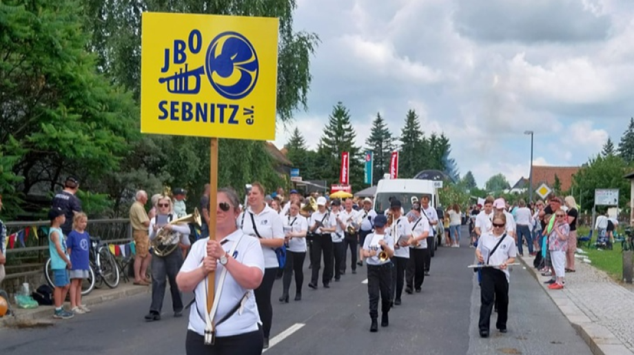 Blasorchester beim Umzug mit Publikum am Straßenrand